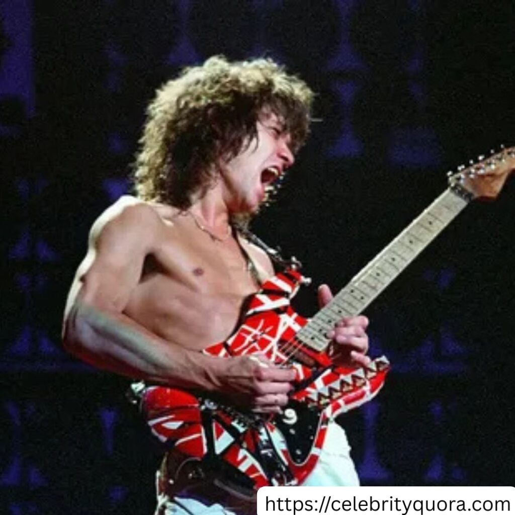 
A photo shows Eddie Van Halen holding a guitar. He is wearing a patterned shirt.