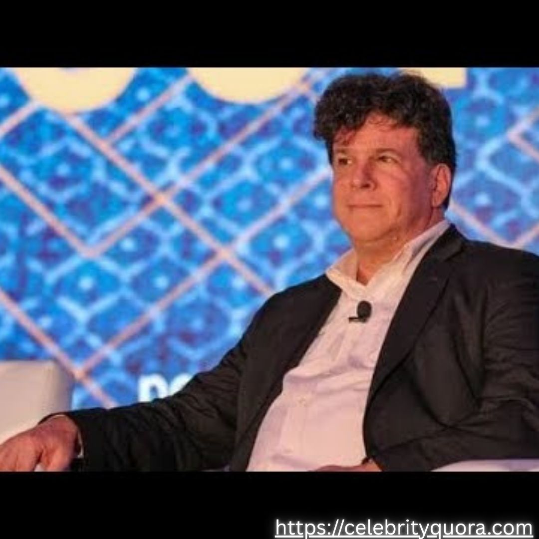 Purple Gradients Beauty and Skincare Product Feature Instagram Post (20) Eric Weinstein is shown in a medium shot, with his dark, curly hair and a light-colored shirt visible. He is wearing a black suit jacket and appears to be speaking at an event.