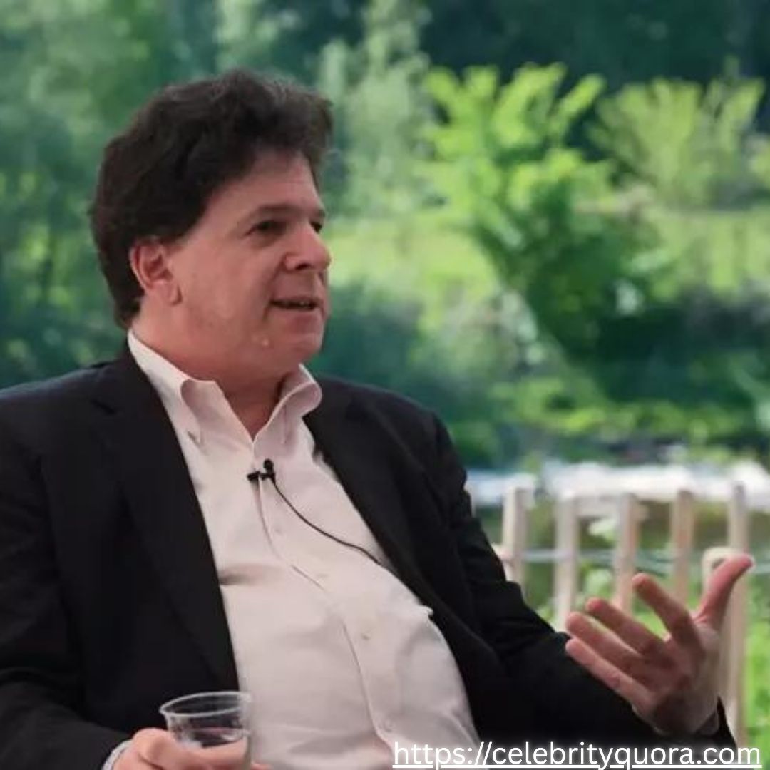 Purple Gradients Beauty and Skincare Product Feature Instagram Post (21) A medium shot captures Eric Weinstein, with his dark, wavy hair, gesturing as he speaks outdoors. He is wearing a black suit jacket over a light-colored shirt.