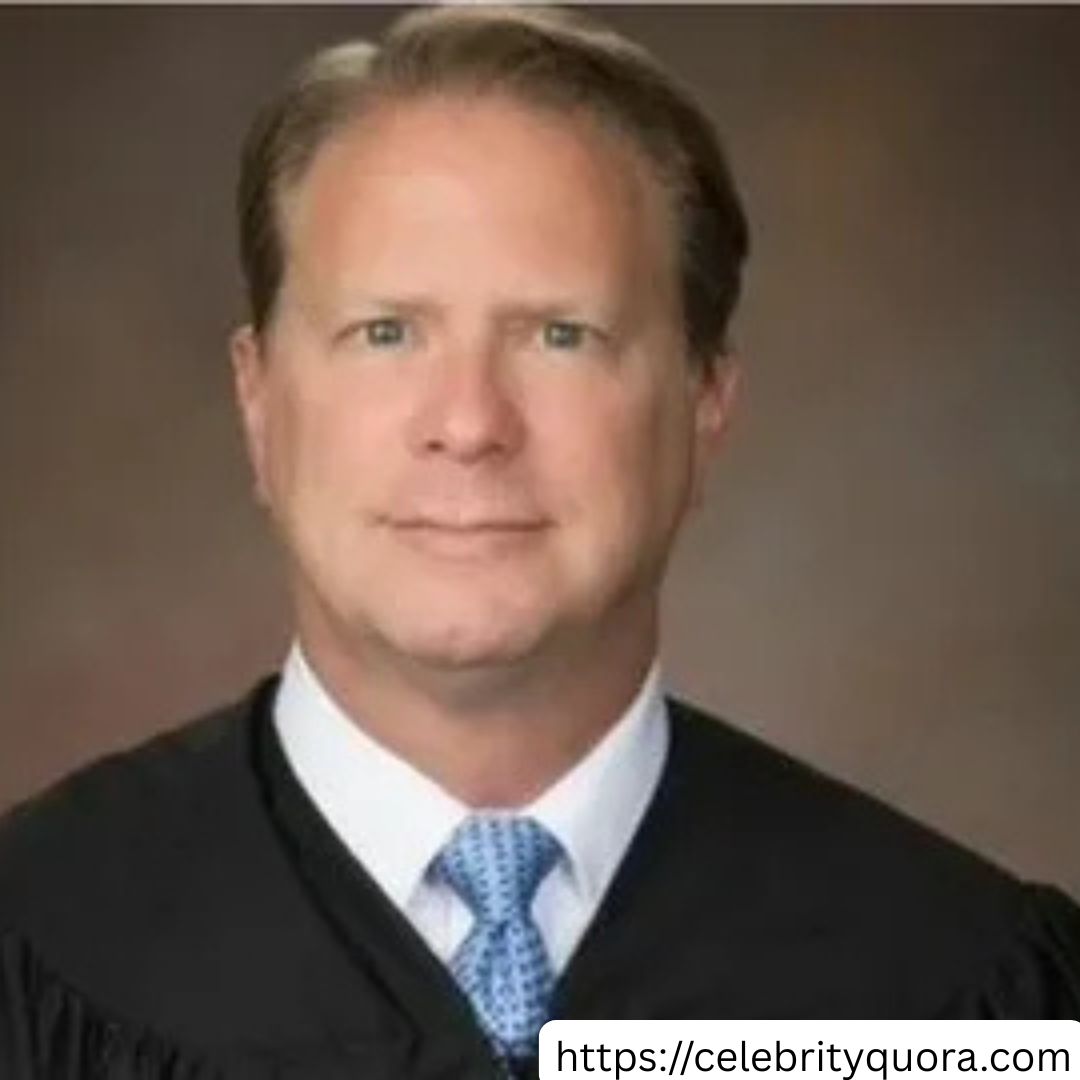 Purple Gradients Beauty and Skincare Product Feature Instagram Post (23) A portrait of Justice Samuel Kent wearing a black judicial robe, a white collared shirt, and a light blue patterned tie. He is looking directly at the camera with a neutral expression.