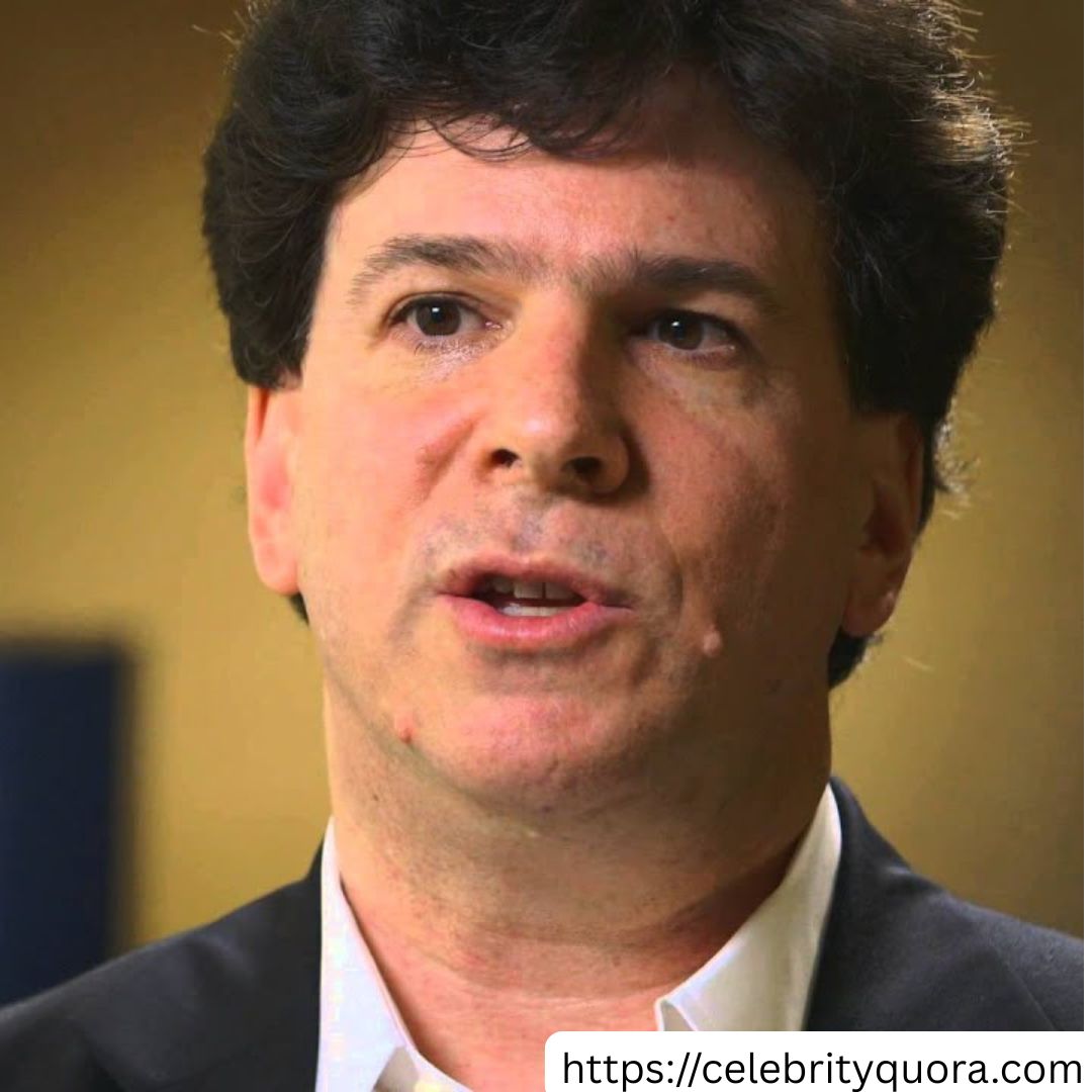 Purple Gradients Beauty and Skincare Product Feature Instagram Post (24) A close-up shot of Eric Weinstein, a middle-aged man with dark, curly hair. He is wearing a dark suit jacket over a white collared shirt. His mouth is slightly open as if he is speaking. He is looking off to the side.