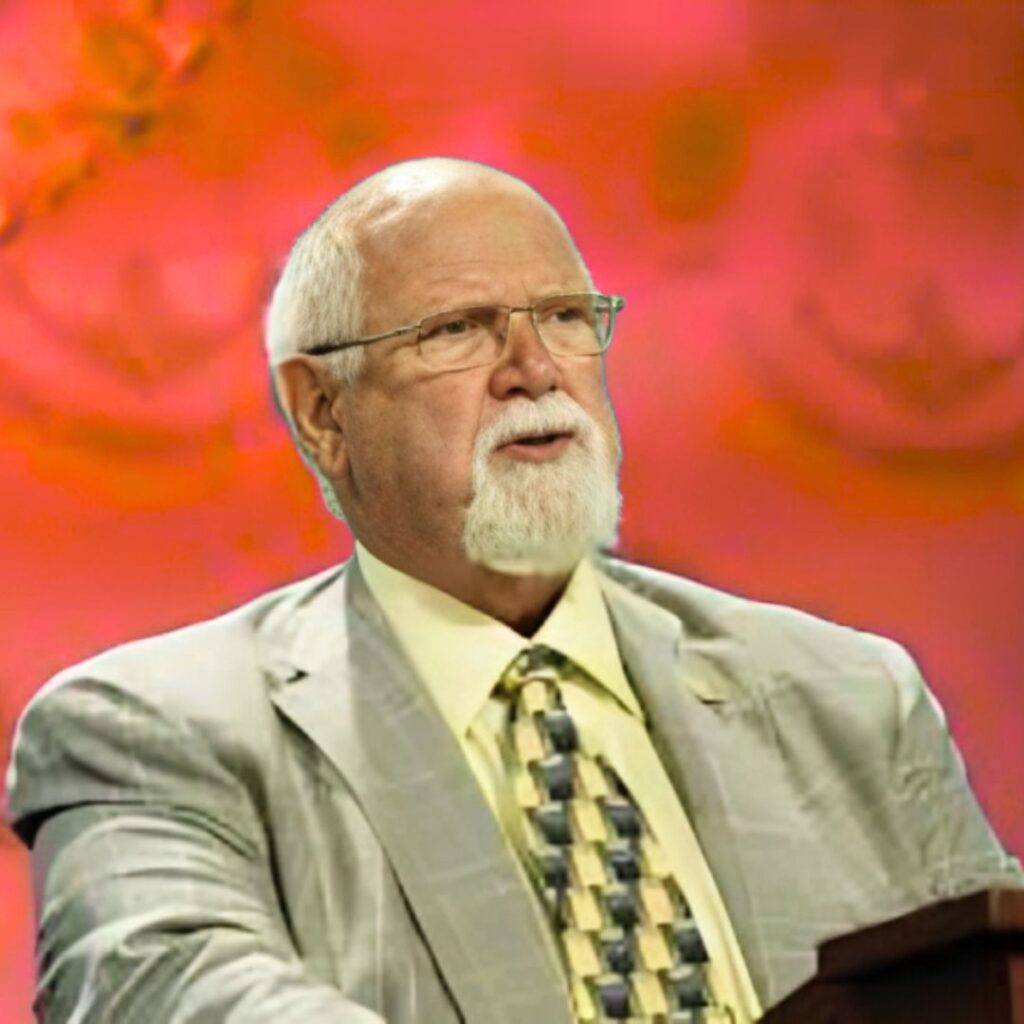 A formal portrait of Harold Daggett with a white beard, wearing a suit and patterned tie, speaking at a podium.