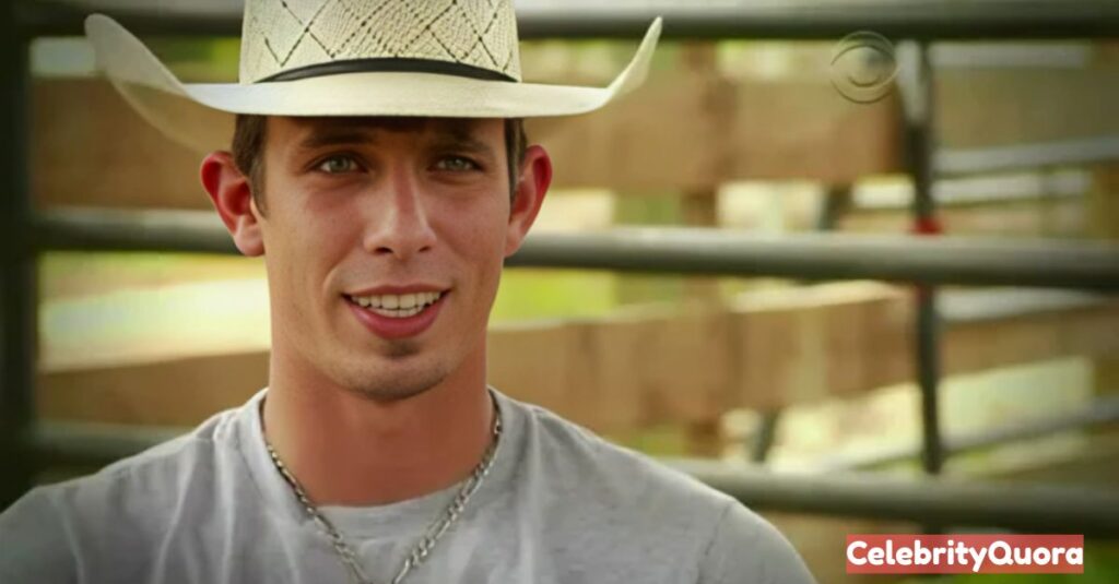 J.B. Mauney, a bull rider, smiling at the camera and wearing a light-colored woven cowboy hat and a grey t-shirt. The background is a blurred image of a wooden fence.
