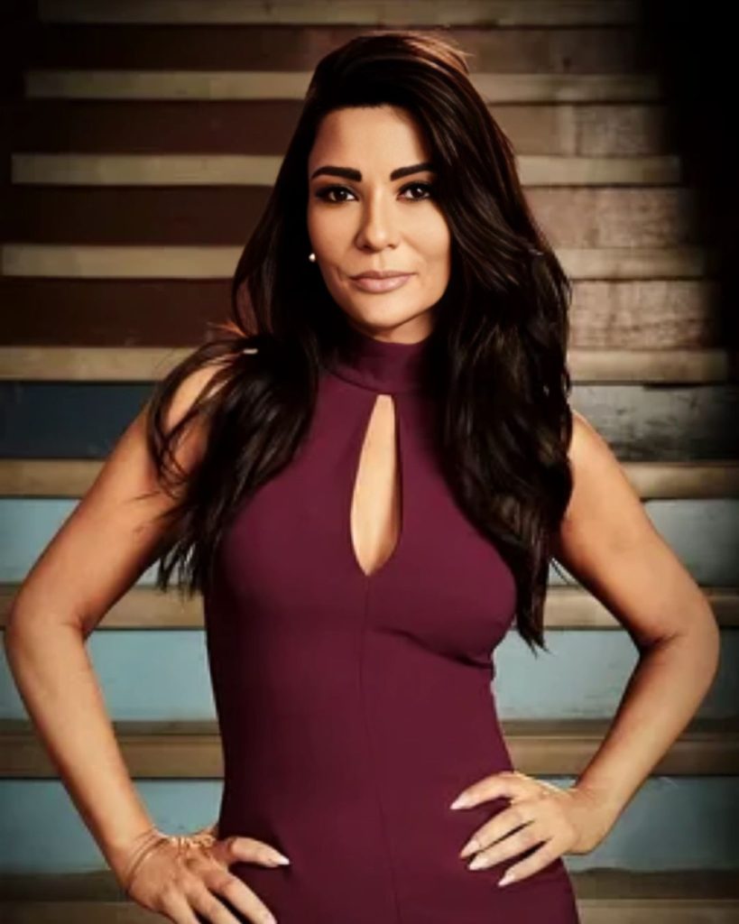 
A portrait of actress Marisol Nichols with long, dark hair, wearing a high-necked burgundy dress with a keyhole cutout at the chest.