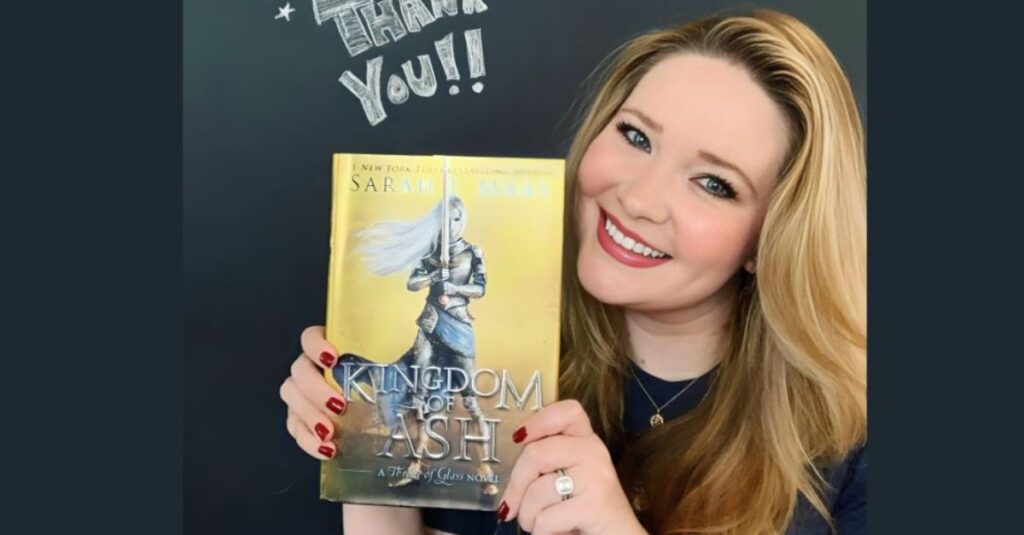she is holding book " Kingdom of Ash " in her hand.