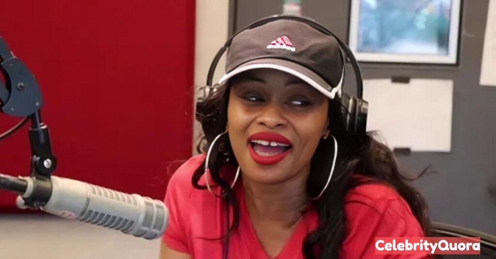 Tokyo Toni in a radio studio, wearing a red t-shirt, a black baseball cap, and headphones, speaking into a microphone. The "Power 99" logo is visible on the equipment.