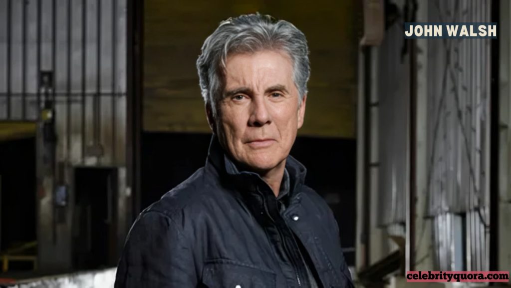 A headshot of a smiling John Walsh wearing a black turtleneck and black jacket, with a "FOX ALLSTAR PARTY" backdrop behind him.
