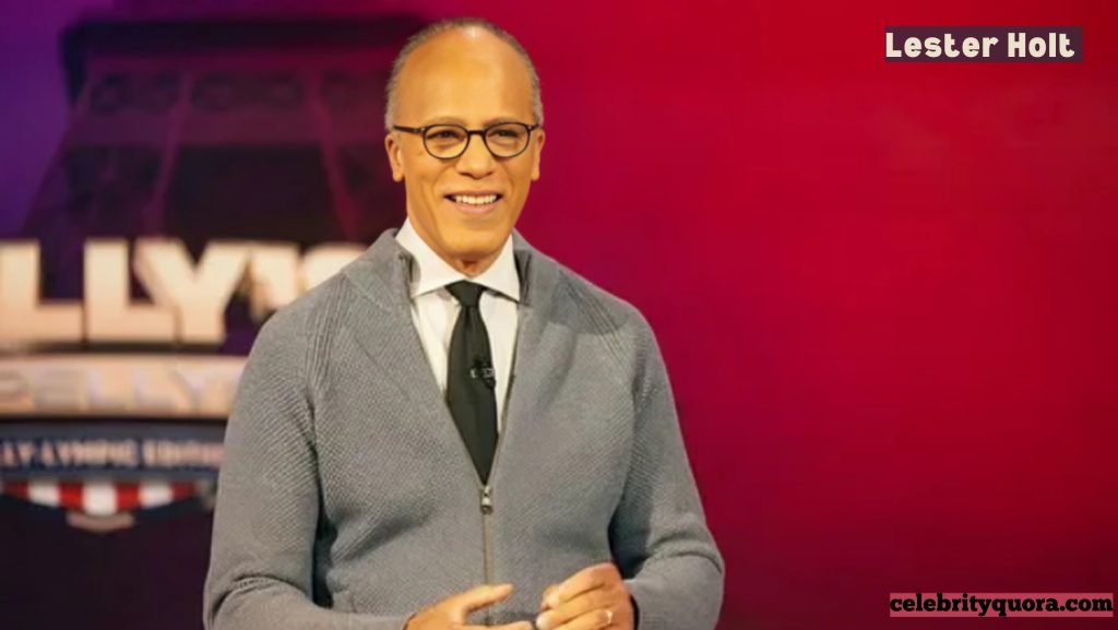 Lester Holt smiling in a studio, wearing a gray zippered cardigan over a white shirt and black tie, with a red background.