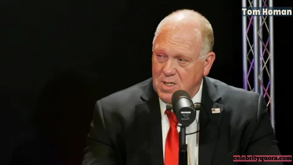 A professional headshot of Tom Homan, a former acting director of ICE, speaking into a microphone with a serious expression. He is wearing a black suit and a red tie.