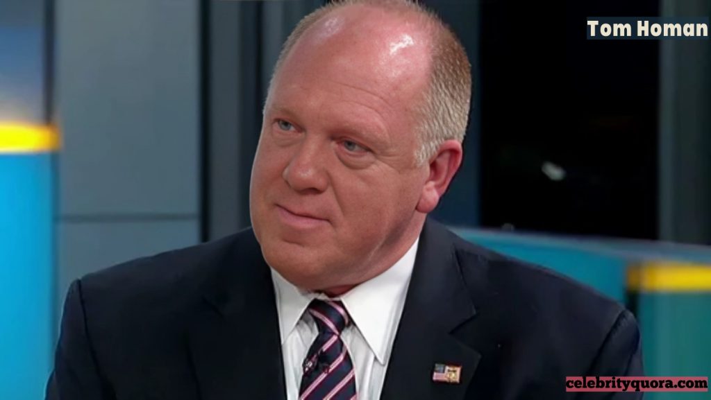 Headshot of Tom Homan, with a somewhat pensive look on his face. He is wearing a dark suit with a striped tie and a small American flag pin on his lapel.
