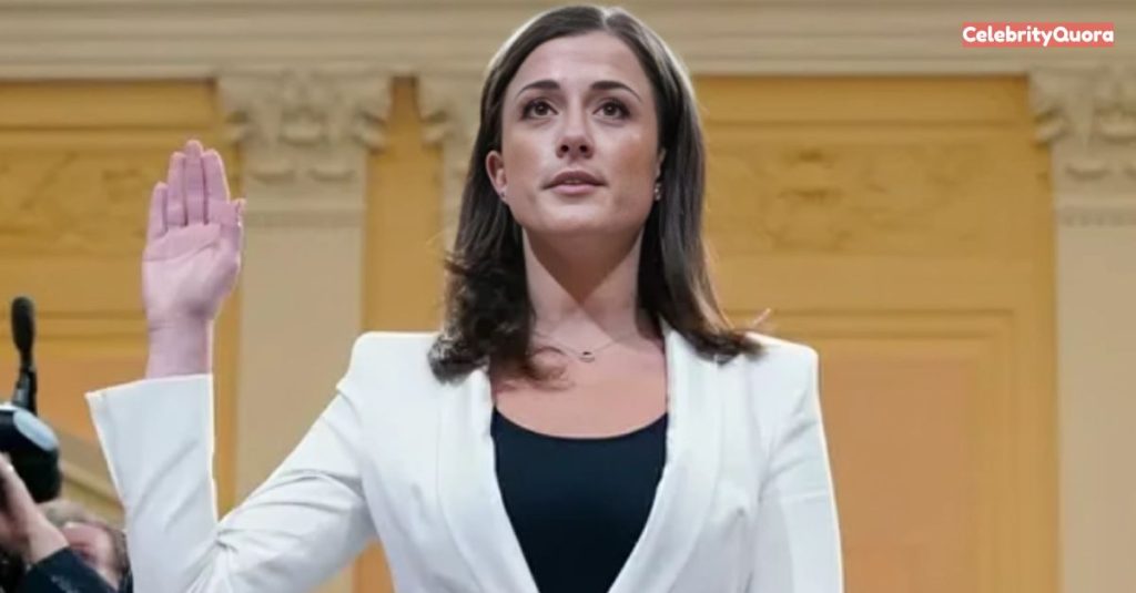 Cassidy Hutchinson is shown under oath, with her hand raised. She wears a white blazer over a black top and a small, delicate necklace. 